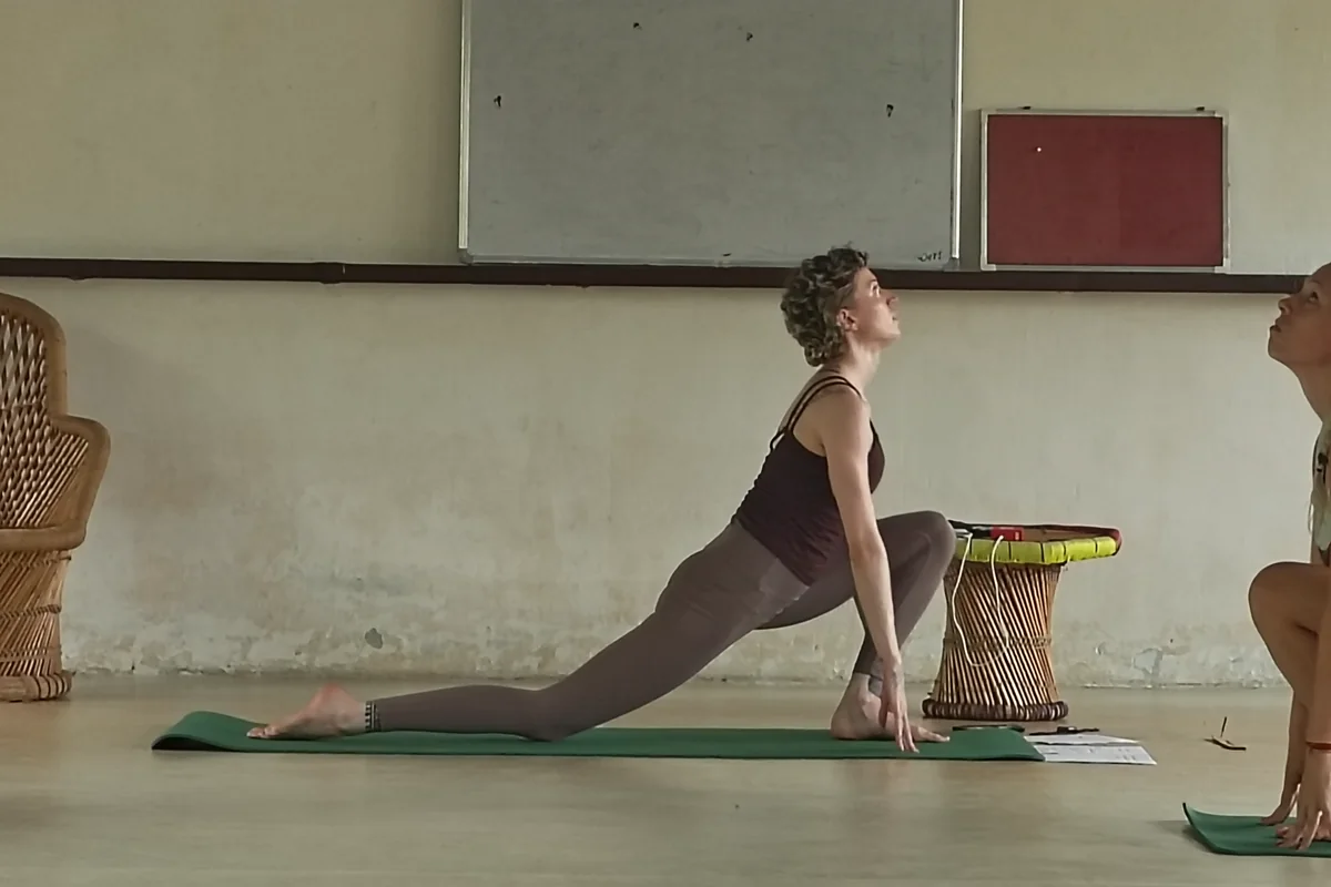 Student practising a low lunge asana in the yoga hall