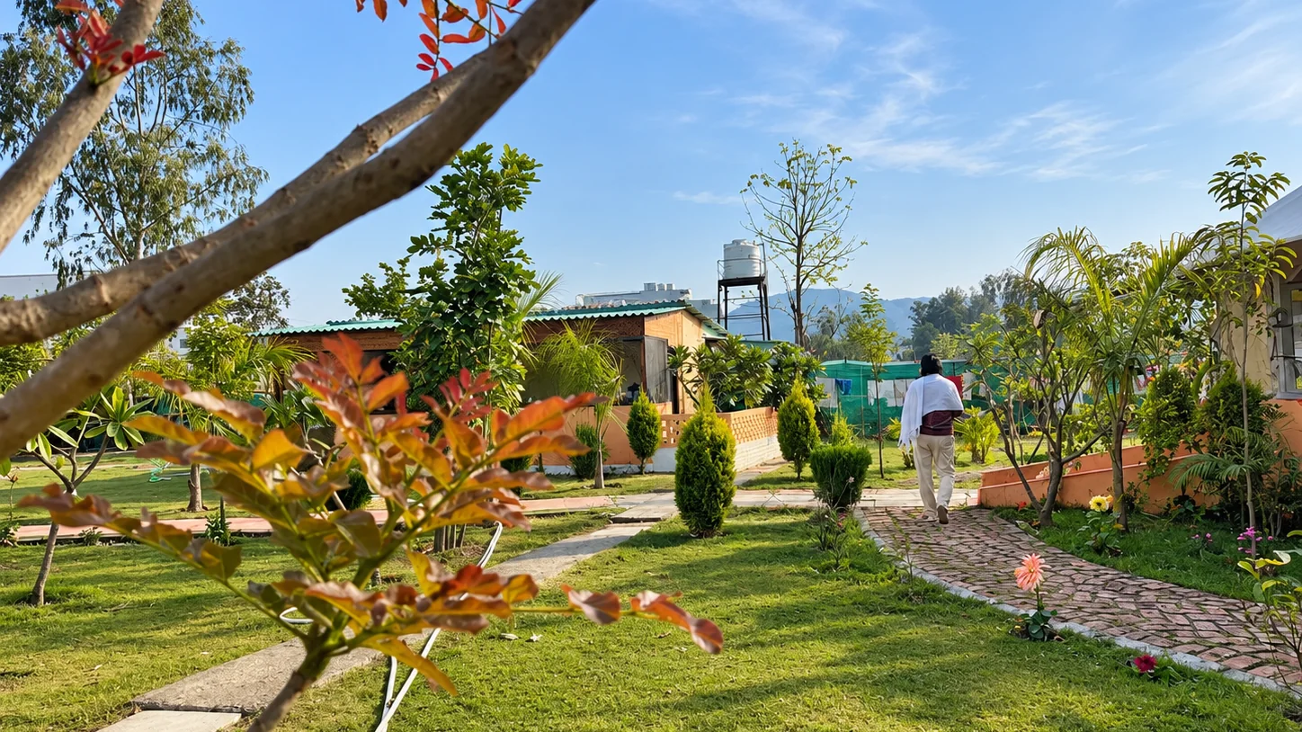 Rishikesh safety starts with where you stay: a person in a white shawl walks a garden path on the Triguna campus